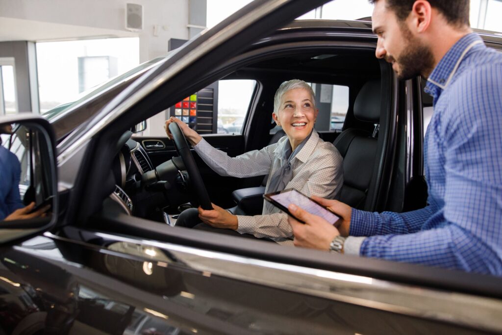 Senhora comprando um carro 0 km e o vendedor de carros ao seu lado