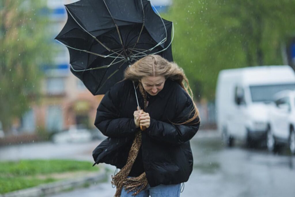 Mulher carregando um guarda-chuva quebrado em meio a uma tempestade