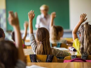 Sala de aula. com crianças com a mão levantada, professor na frente