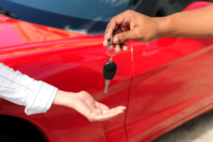 mão entregando a chave de um carro para o compradoor