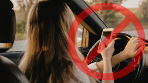 Uma motorista segurando o celular em frente ao volante